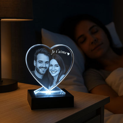Bloc cœur en verre avec gravure 2D “Je t’aime” et portrait de couple, posé sur un socle lumineux. Cadeau original à offrir pour un moment spécial à deux.