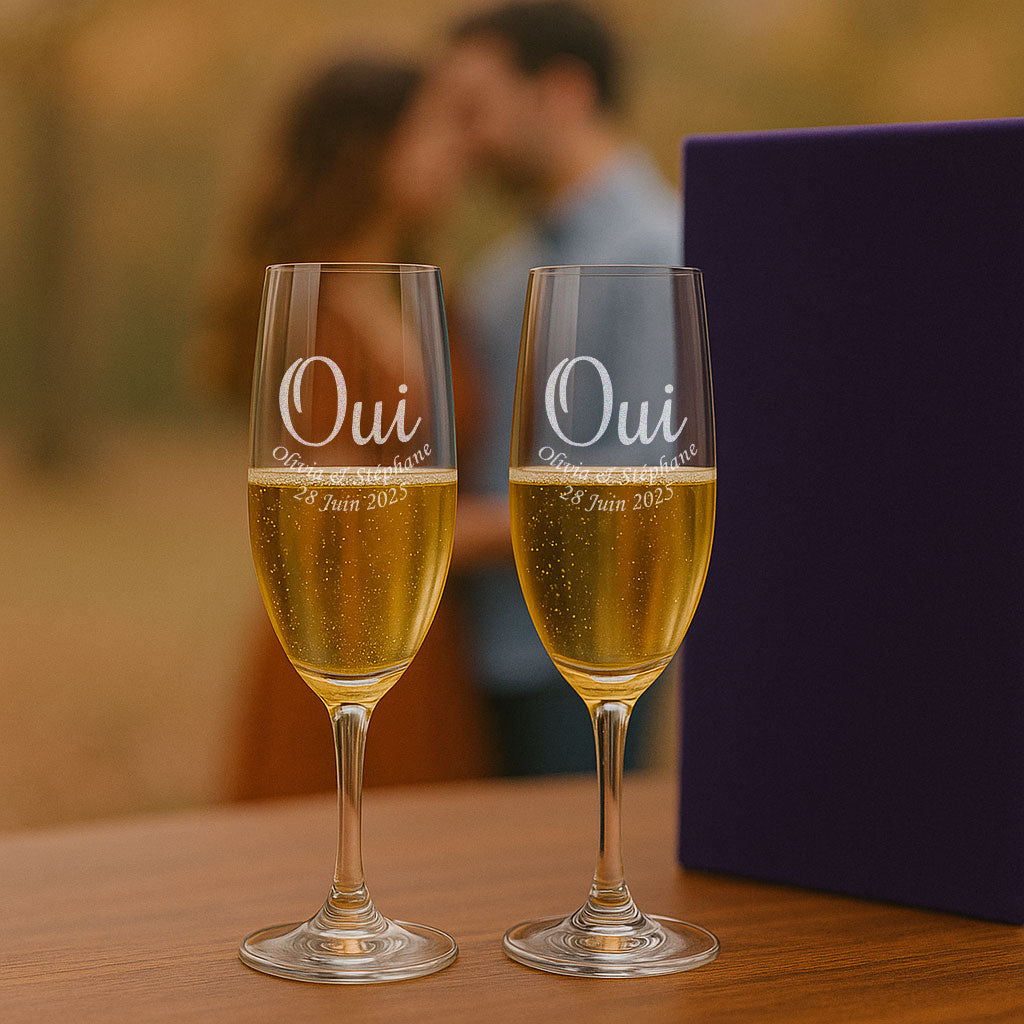 Deux flûtes à champagne gravées "OUI", posées devant un couple de mariés. Un cadeau romantique et unique pour célébrer le plus beau jour de leur vie.