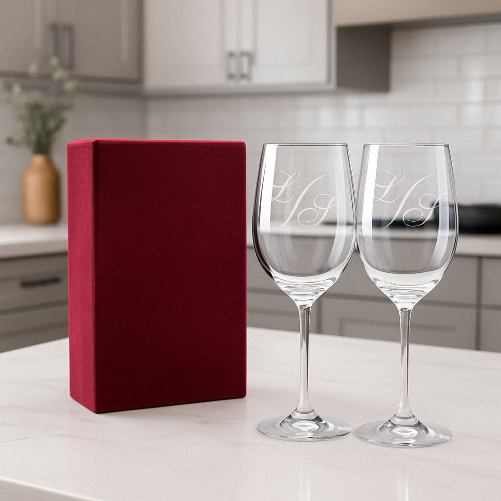Coffret cadeau contenant deux verres à vin personnalisés avec des initiales gravées en monogramme, présenté avec un élégant écrin rouge velours.