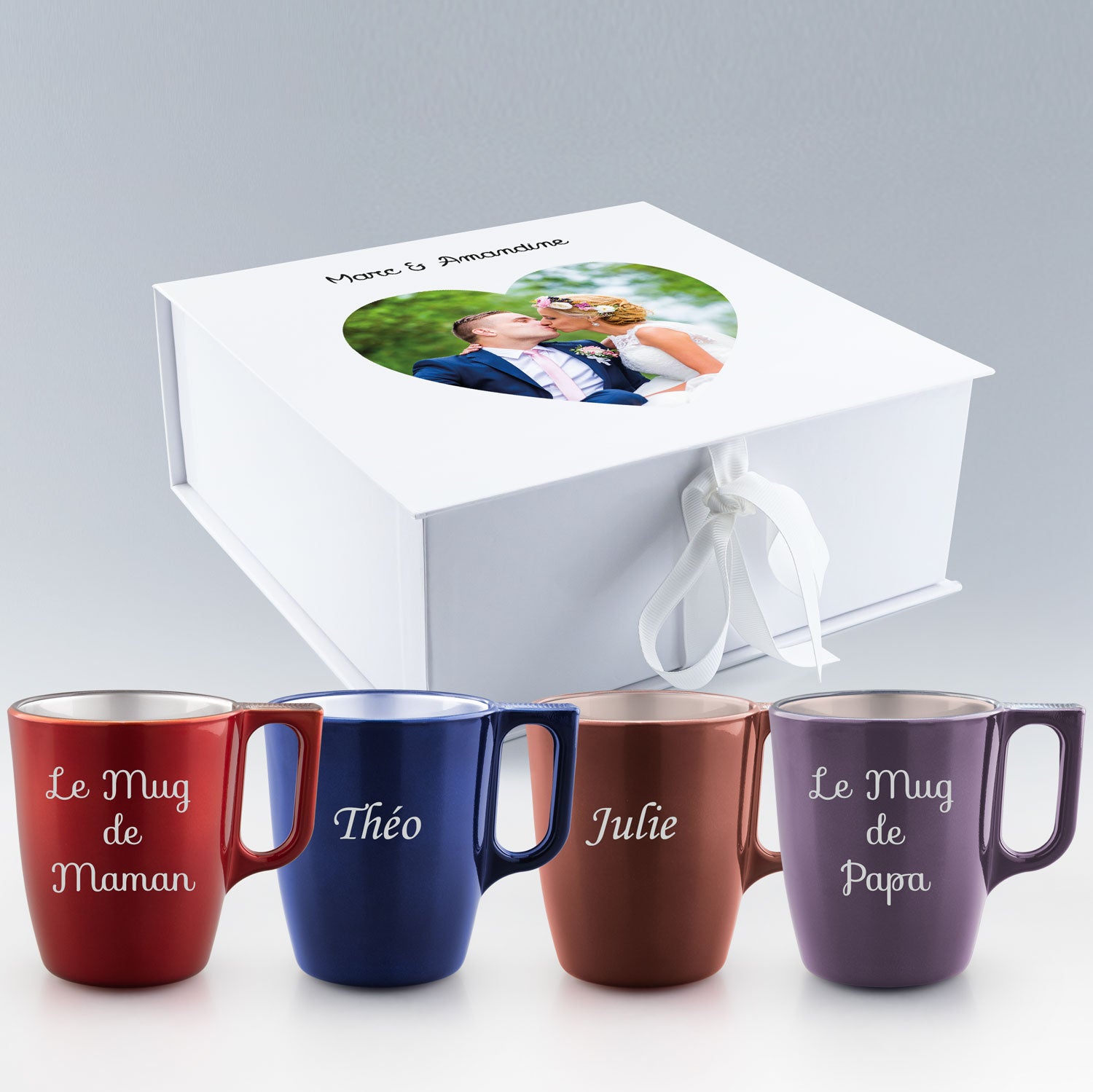 Coffret blanc personnalisé avec une photo de mariage sur le couvercle, accompagné de quatre mugs colorés gravés avec des prénoms et messages familiaux.