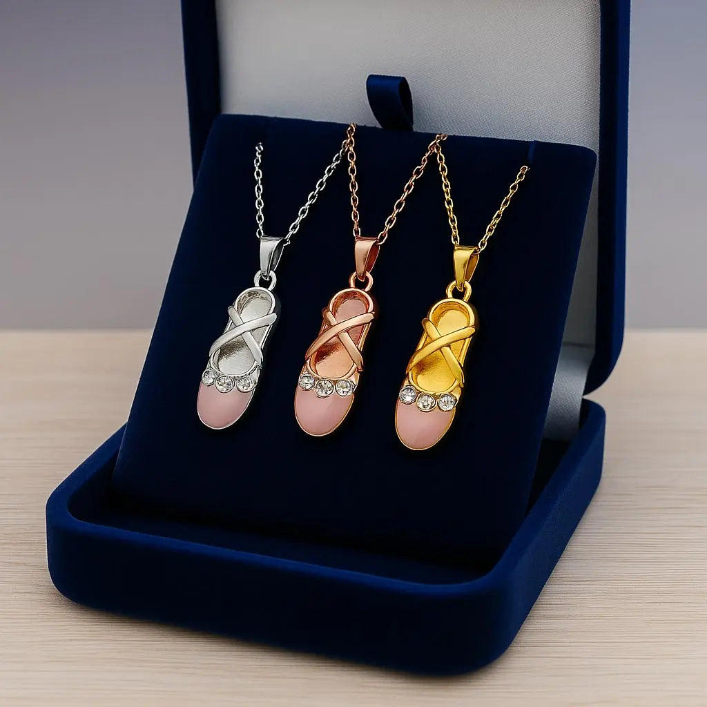 Coffret contenant trois pendentifs ballerine : doré, argenté et rose doré, chacun orné de cristaux Swarovski® scintillants.