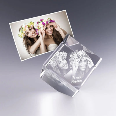 Cube en verre pan coupé de 6 cm avec gravure laser 3D de deux sœurs souriantes portant des couronnes de fleurs, message personnalisé “À ma sœur”. Cadeau gravé unique et émotionnel.