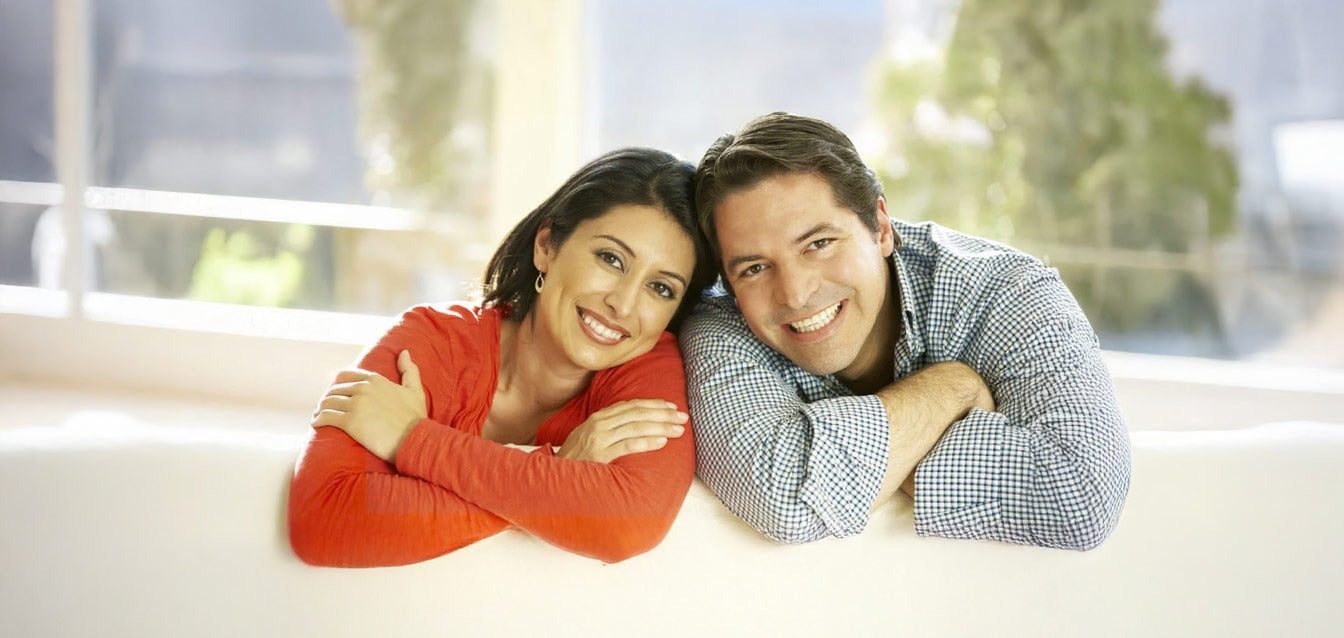 Couple souriant allongé sur un canapé, photo lumineuse idéale pour créer une gravure 3D personnalisée dans un bloc en verre.