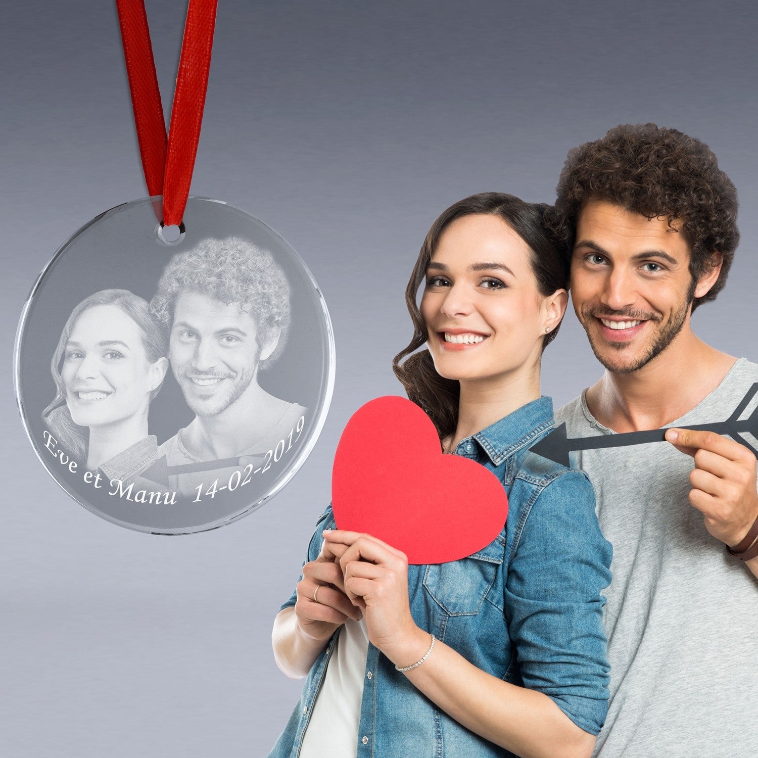 Médaillon en verre rond suspendu par un ruban rouge, gravé avec un portrait de couple et la date "14-02-2019", présenté comme un cadeau romantique à suspendre.