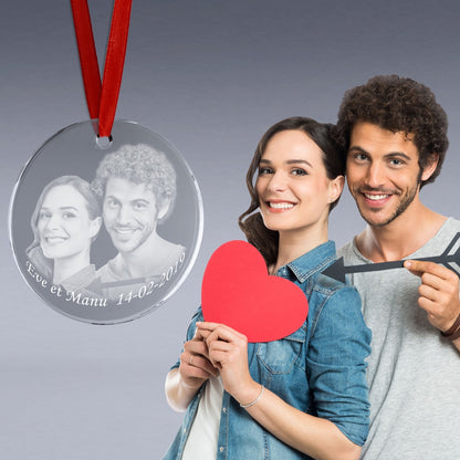 Médaillon en verre rond suspendu par un ruban rouge, gravé avec un portrait de couple et la date "14-02-2019", présenté comme un cadeau romantique à suspendre.