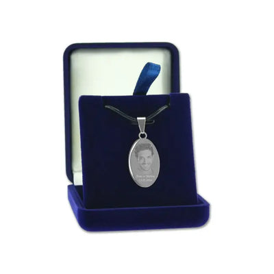 Pendentif ovale en finition argent avec photo gravée, présenté sur un cordon noir dans un écrin bleu velours ouvert.