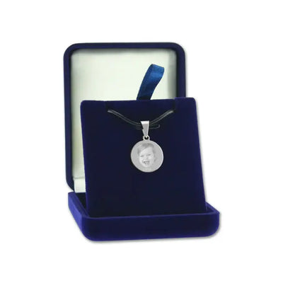 Pendentif rond en métal argenté avec photo gravée, présenté dans un écrin bleu – un cadeau personnalisé plein d’émotion.