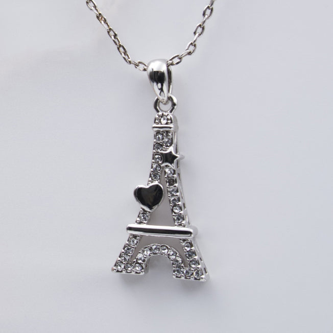 Détail du pendentif Tour Eiffel Cœur en métal argenté, incrusté de strass étincelants et orné d’un cœur noir.