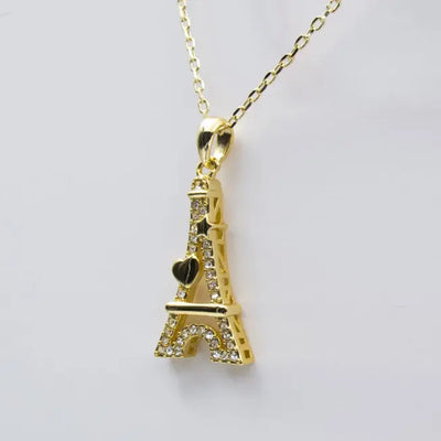 Pendentif doré en forme de Tour Eiffel avec cœur et étoile, décoré de pierres brillantes, monté sur chaîne fine.