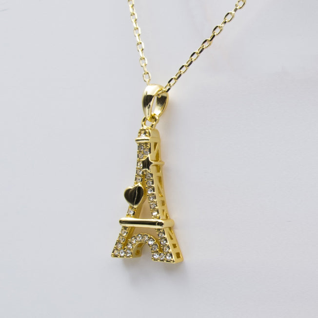 Pendentif doré en forme de Tour Eiffel avec cœur et étoile, décoré de pierres brillantes, monté sur chaîne fine.